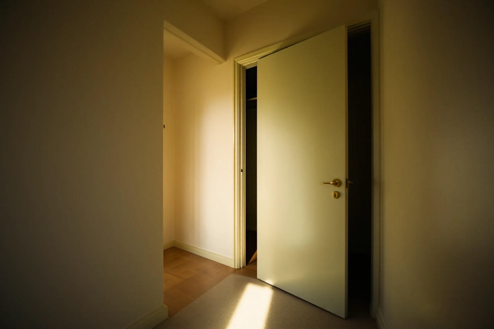 A closet door in a child's bedroom, open a hand's width onto darkness, seen from bed height.